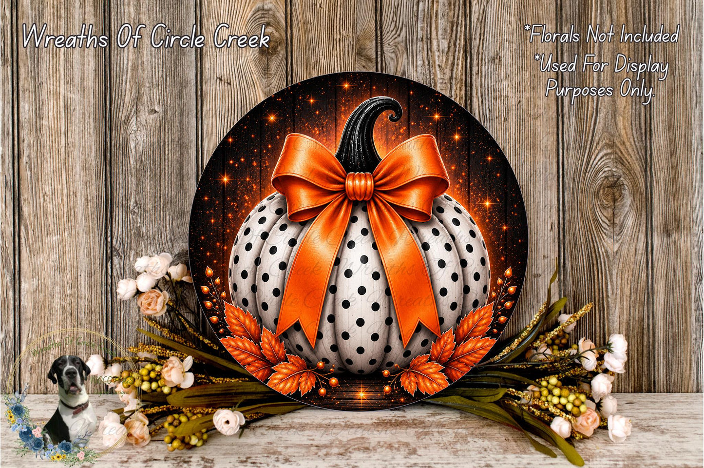 A decorative wreath featuring a large white pumpkin with a black bow, surrounded by orange leaves and flowers, placed on a wooden surface.