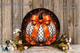 A decorative wreath featuring a large white pumpkin with a black bow, surrounded by orange leaves and flowers, placed on a wooden surface.