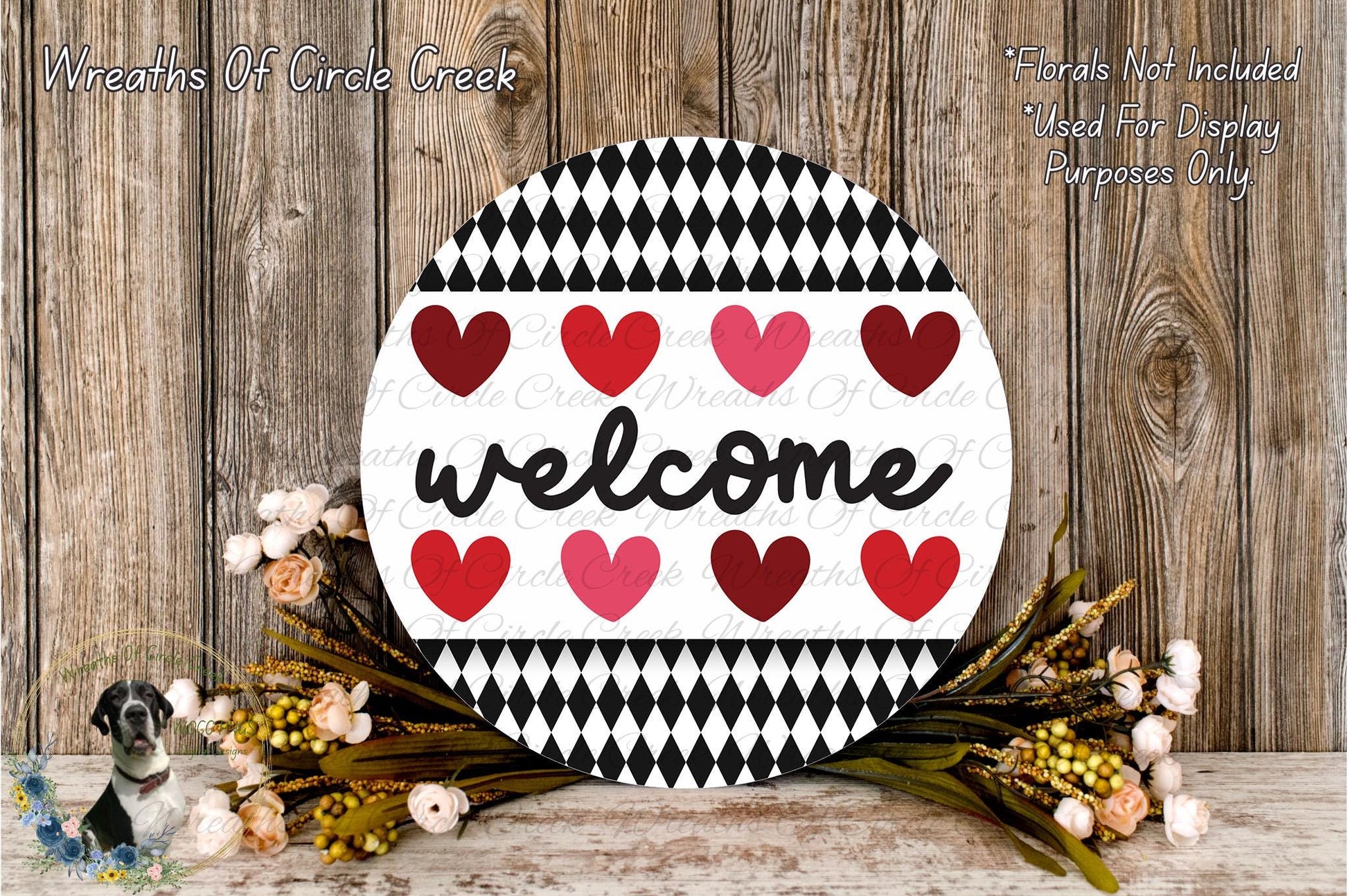 a round sign with the word "welcome" written on it, surrounded by a wreath of flowers and a wooden background.