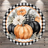 A circular arrangement of pumpkins and flowers on a wooden background, with a black and white checkered border.