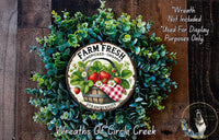 a wreath made of various green plants, including a basket of strawberries, with a sign that reads "Farm Fresh Handpicked Organic Strawberries".