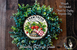 a wreath made of various green plants, including a basket of strawberries, with a sign that reads "Farm Fresh Handpicked Organic Strawberries".