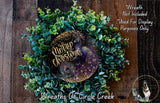 A wreath made of green and purple plants, with a gold and purple peacock feather design, and the text "Merry Christmas" written on it.