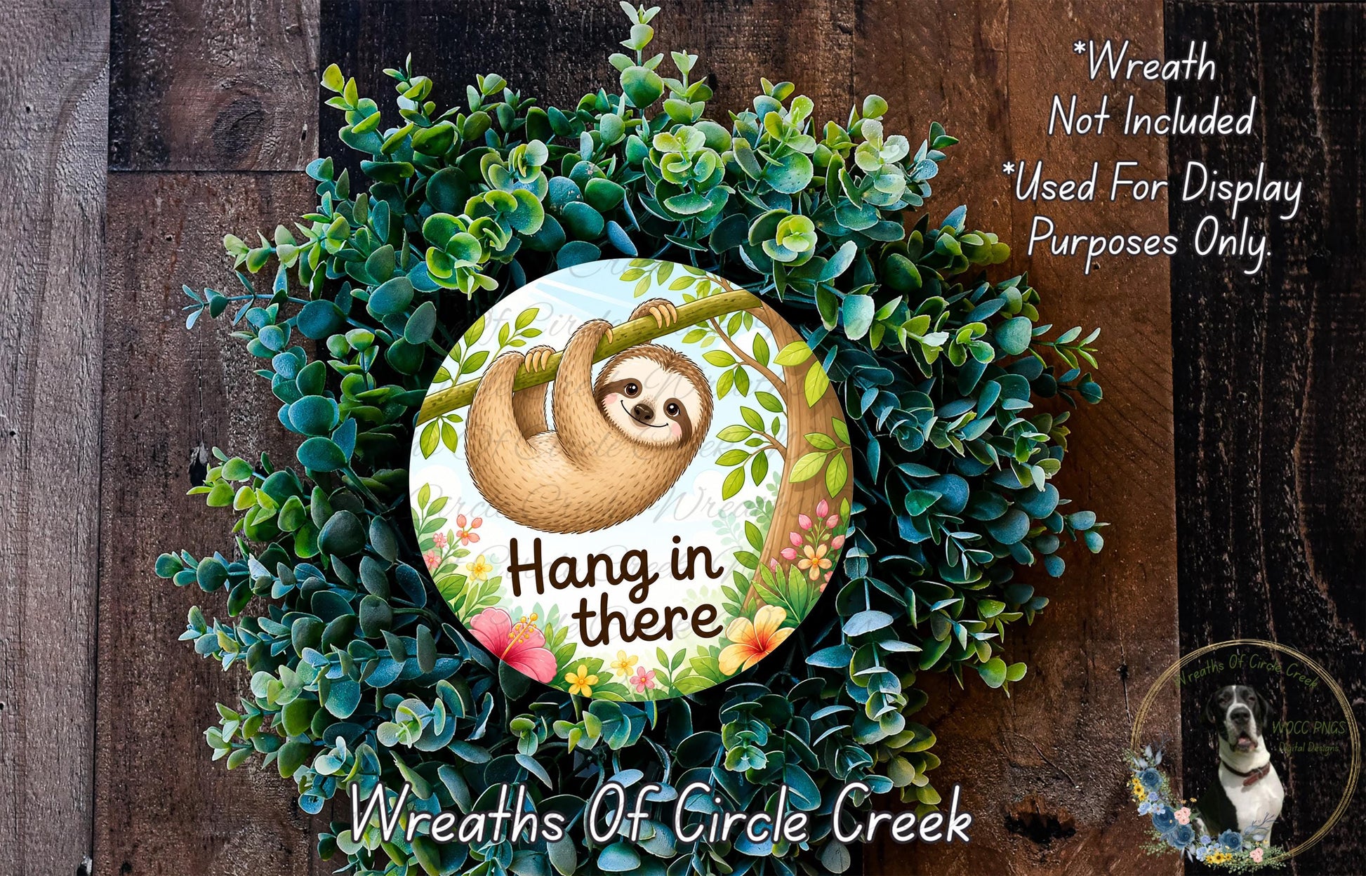 A wreath made of green foliage and flowers, with a sloth hanging from a branch and the text "Hang in there" written on it.