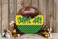 A wooden sign with a football on it, surrounded by a wreath of flowers and greenery, with the text "game day" displayed on the sign.