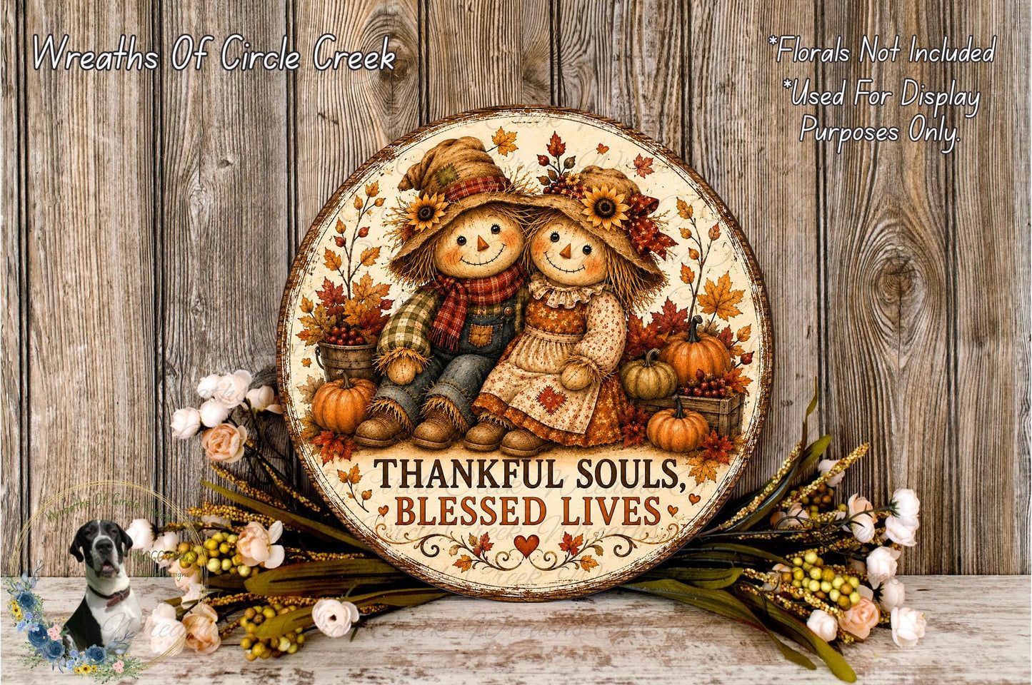 a round wooden plaque with a painting of two scarecrow figures, surrounded by autumn decorations such as pumpkins and flowers. The plaque has a message that reads "Thankful Souls, Blessed Lives".