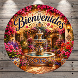 a beautifully decorated outdoor space with a fountain, surrounded by colorful flowers and plants. The text "Bienvenidos" is prominently displayed, indicating a welcoming message.