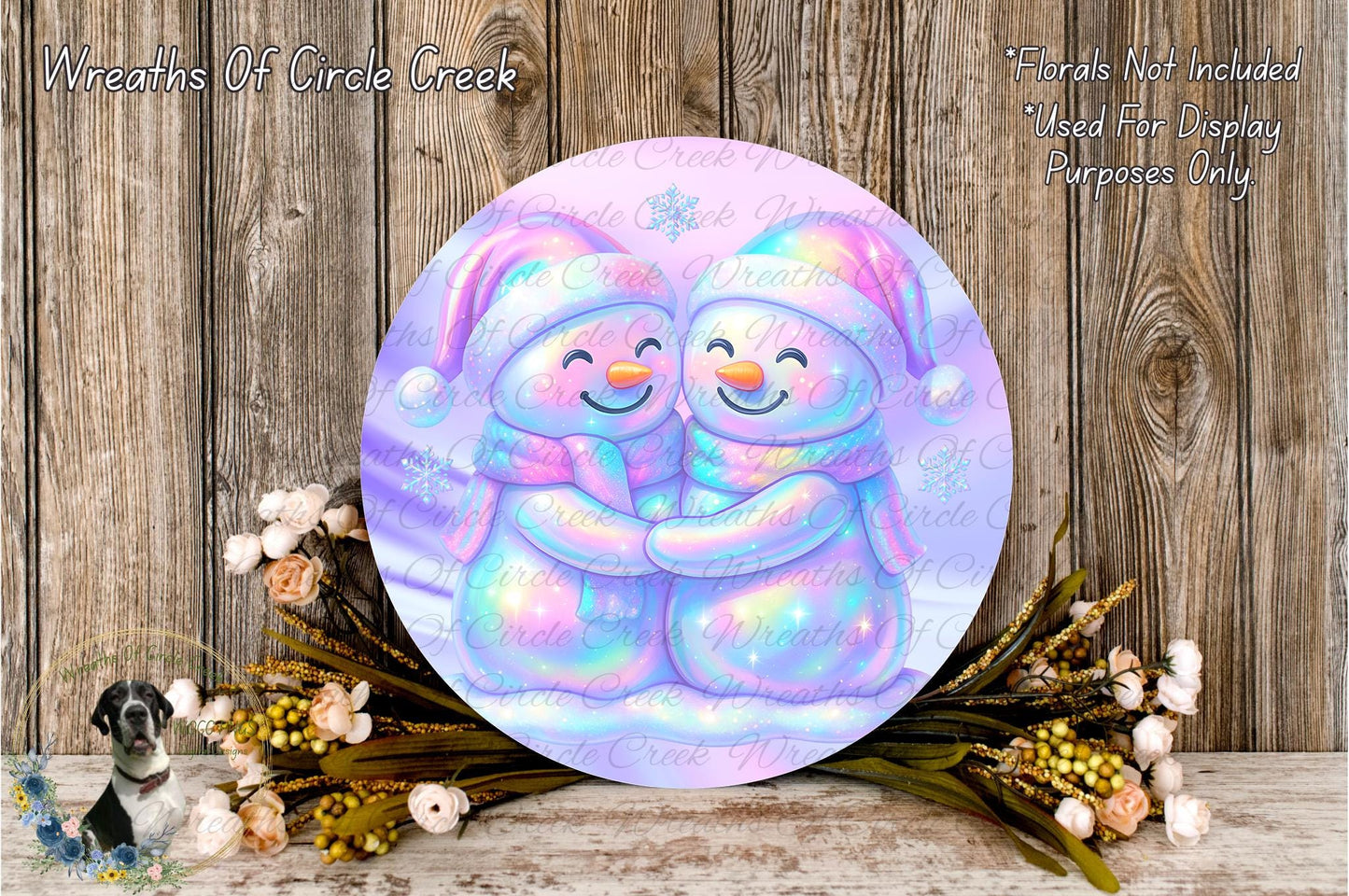 A round, colorful wreath with two smiling snowmen on it, surrounded by flowers and placed on a wooden surface.