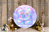 A round, colorful wreath with two smiling snowmen on it, surrounded by flowers and placed on a wooden surface.