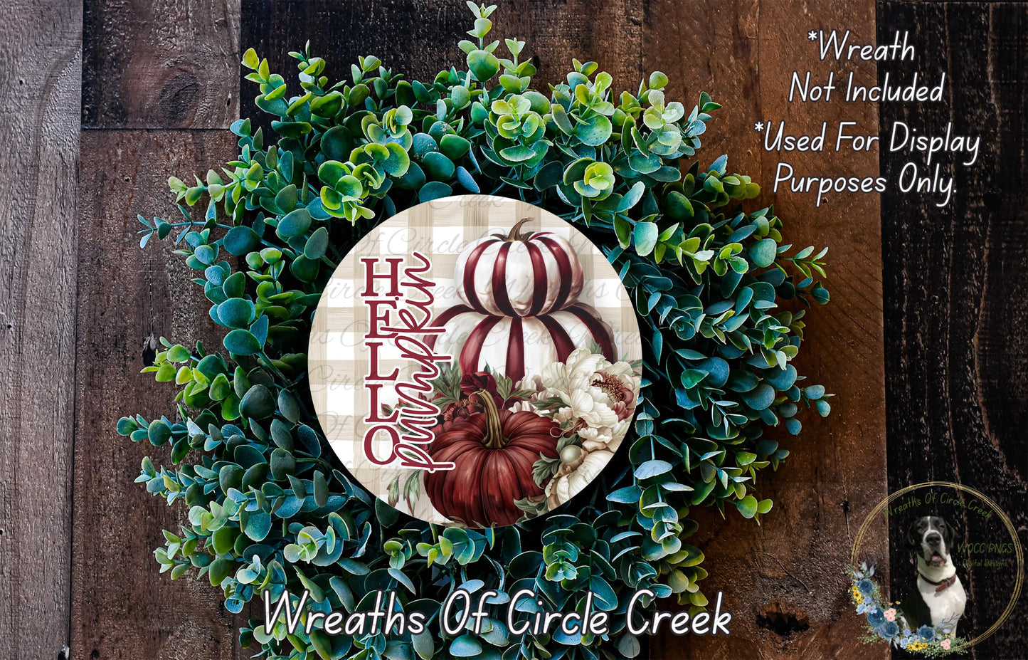 a wreath made of various green and brown foliage, including pumpkins and flowers, displayed on a wooden surface.