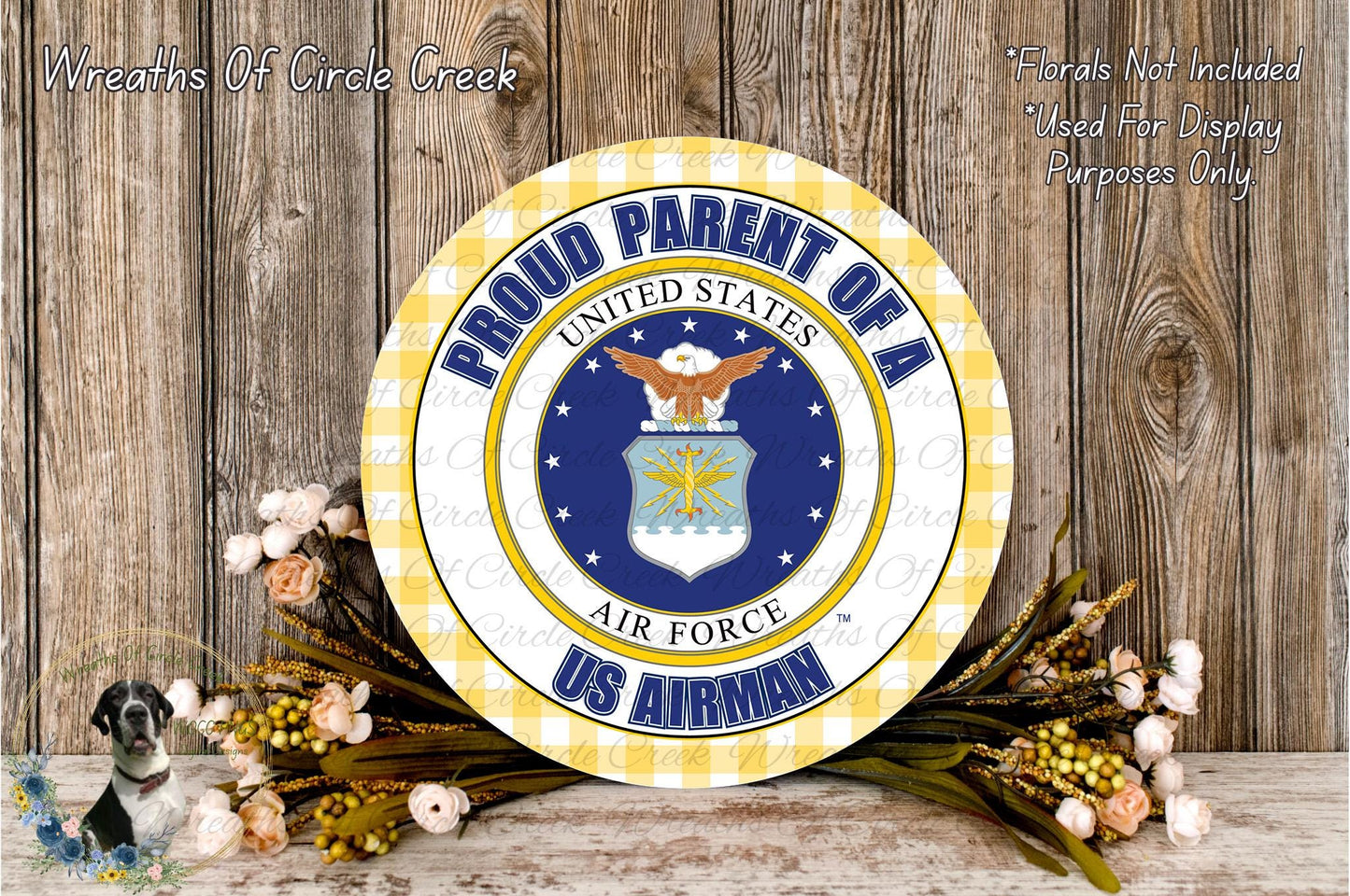 a patriotic wreath with the text "Proud Parent of a US Airman" and the Air Force seal, surrounded by flowers and a wooden background.