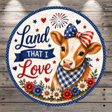 a cow wearing a patriotic bow tie and surrounded by flowers and stars, with the text "Land that I Love" displayed on a circular background.