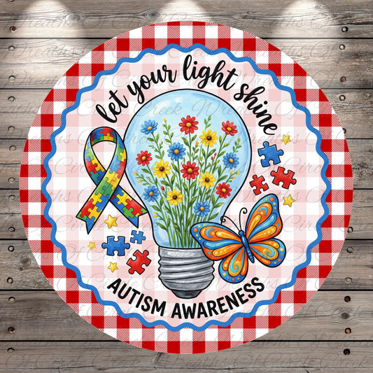 A round sign with a checkered border and a light bulb containing flowers, surrounded by puzzle pieces and a butterfly. The sign features a message about Autism Awareness.