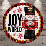 A cheerful illustration of a nutcracker soldier with a hat and a message that says "Joy to the World" against a red and gold background with snowflakes.