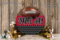 A wooden sign with a football on it, surrounded by a floral arrangement and a red and black polka dot background.