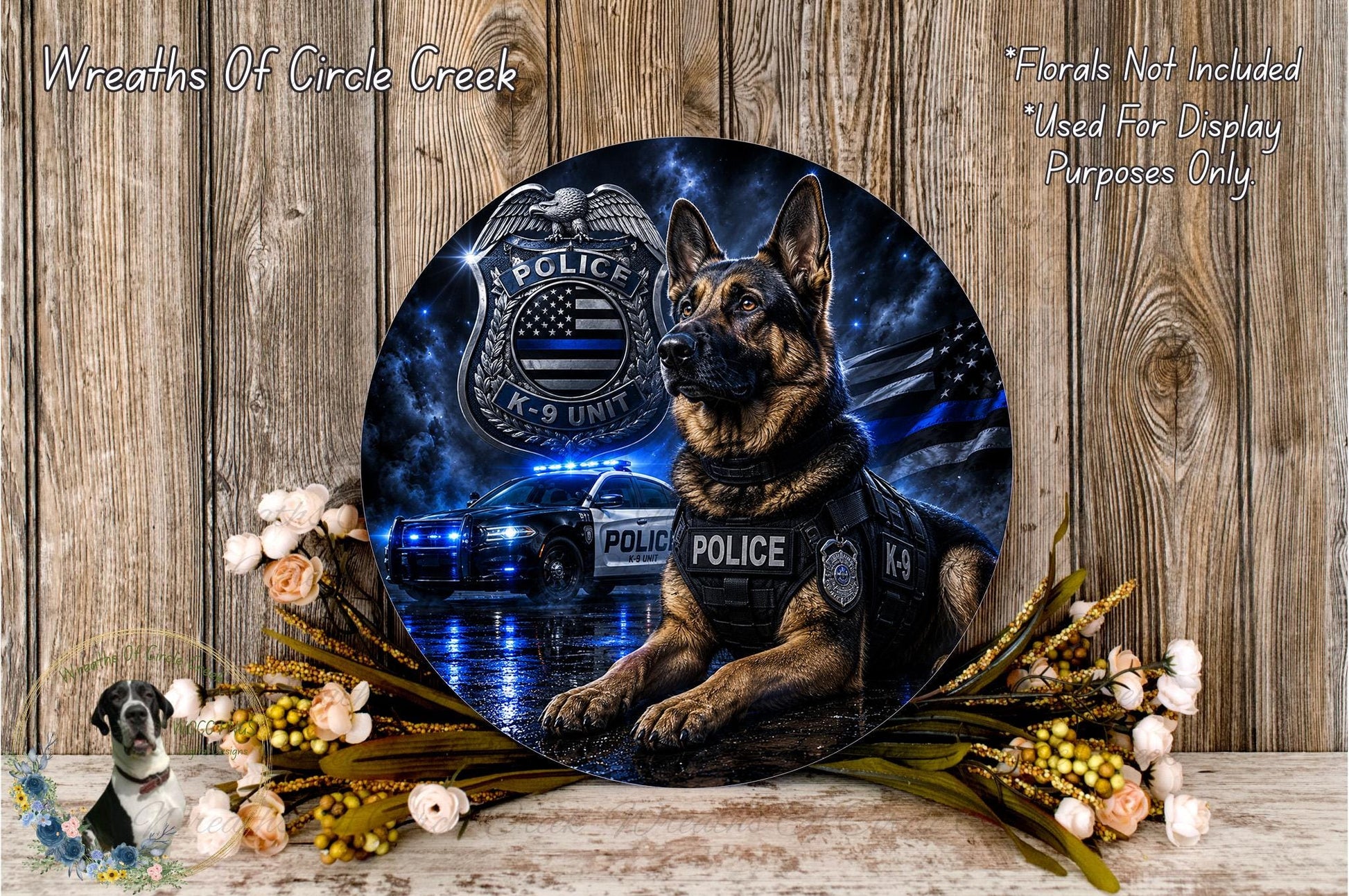 a German Shepherd police dog wearing a police vest, sitting in front of a police car with a police emblem on the hood. The dog is positioned in front of a floral arrangement, and there is a text overlay that reads "Wreaths Of Circle Creek" and "Flowers Not Included Used For Display Purposes Only".