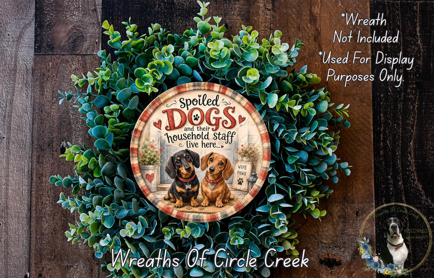 a wreath made of green leaves and a decorative plate with a dog illustration on it, placed on a wooden surface.