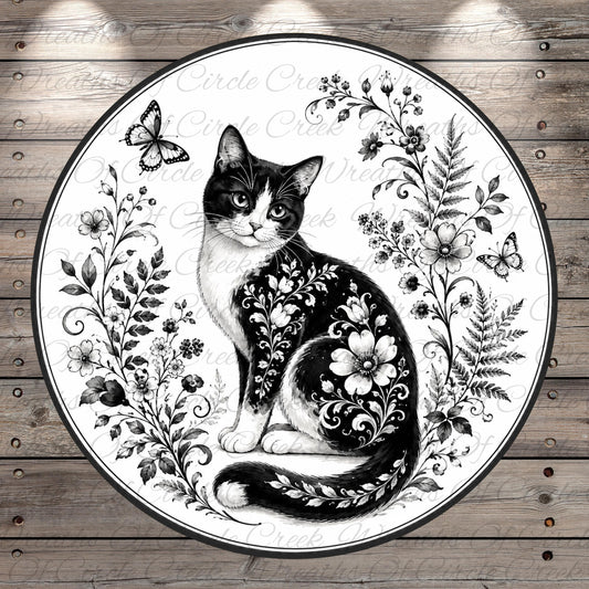 A black and white illustration of a cat with floral patterns on its fur, surrounded by flowers, butterflies, and leaves on a wooden background.