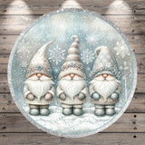 A circular illustration featuring three gnomes wearing winter clothing and hats, set against a snowy background with snowflakes.