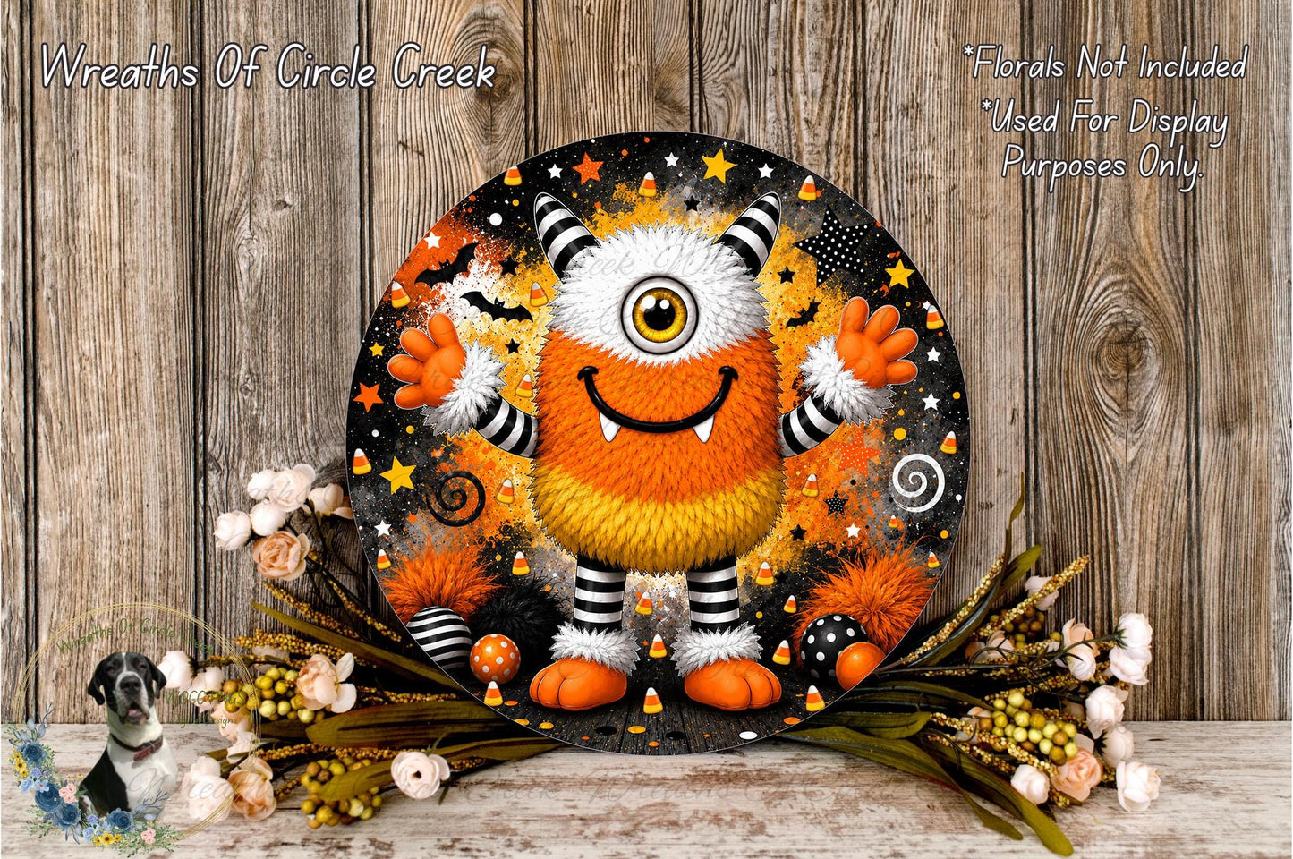 A whimsical, cartoonish monster with a large, round head and a big smile, surrounded by a variety of Halloween-themed elements such as stars, bats, and candy canes. The monster is set against a backdrop of a wooden wall, with a floral arrangement of flowers and greenery placed in front of it.
