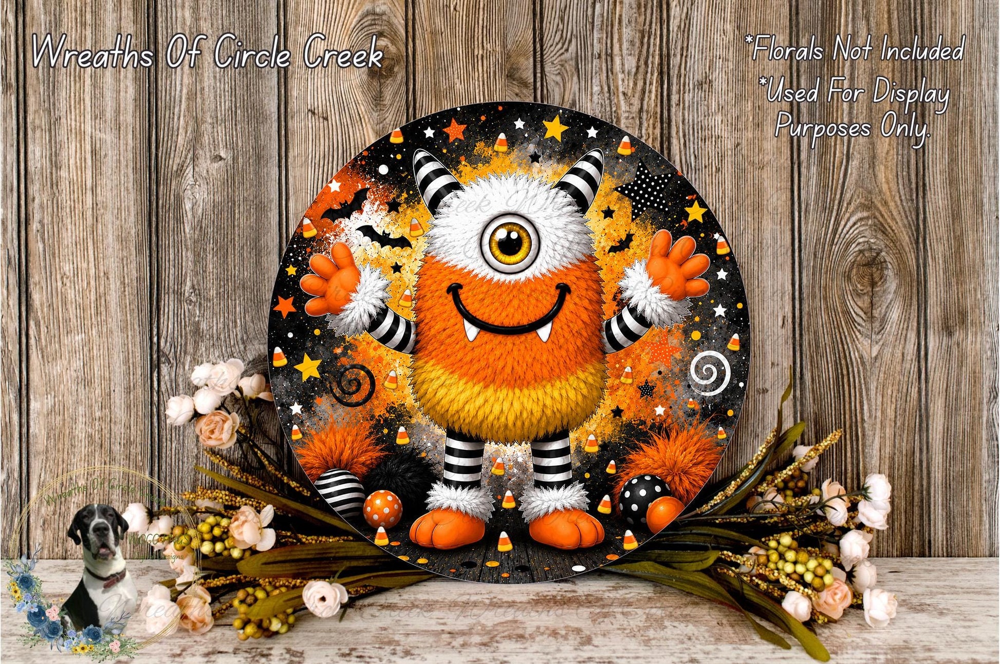 A whimsical, cartoonish monster with a large, round head and a big smile, surrounded by a variety of Halloween-themed elements such as stars, bats, and candy canes. The monster is set against a backdrop of a wooden wall, with a floral arrangement of flowers and greenery placed in front of it.