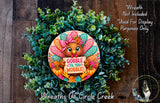 A wreath made of green leaves and a turkey holding a sign that says "GOBBLE TIL YOU WOBBLE!"