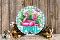 A round sign with a pink flamingo, a glass of pink cocktail, and a palm tree, surrounded by flowers and a wooden background.
