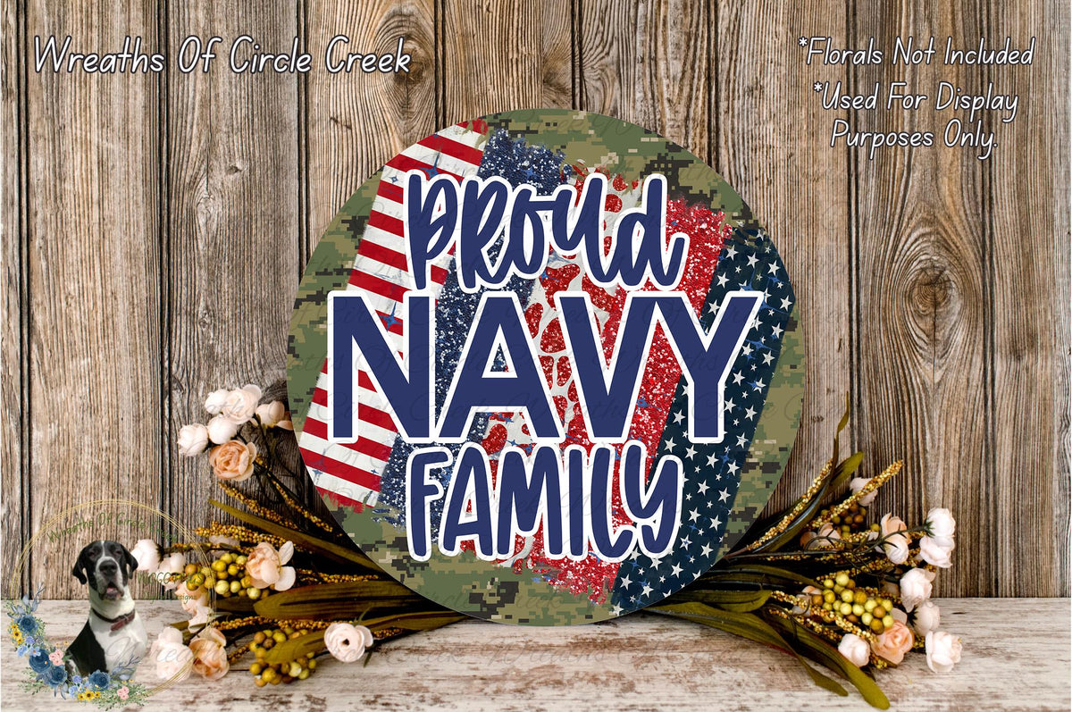 a patriotic-themed wreath with the text "Proud Navy Family" displayed prominently. The wreath is surrounded by a floral arrangement and is set against a rustic wooden background.