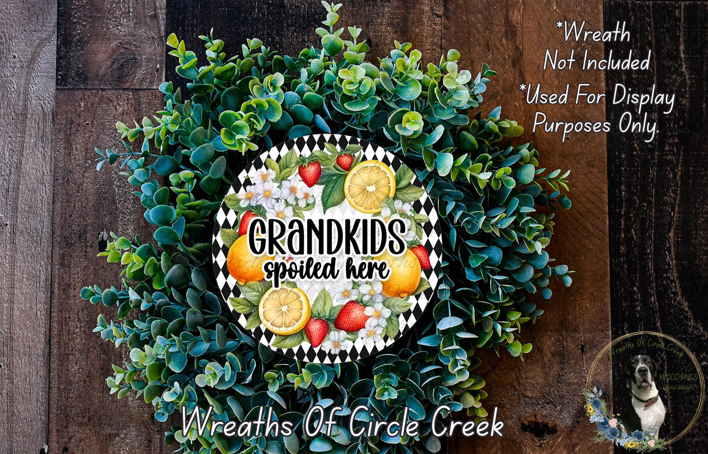A wreath made of various green plants and colorful fruits, including oranges, strawberries, and lemons, with the text "GRANDKIDS SPOILED HERE" prominently displayed.