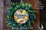 A wreath made of various green plants and colorful fruits, including oranges, strawberries, and lemons, with the text "GRANDKIDS SPOILED HERE" prominently displayed.