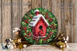 A round wooden wreath with a red birdhouse on top, surrounded by a mix of flowers and greenery, placed on a wooden surface.