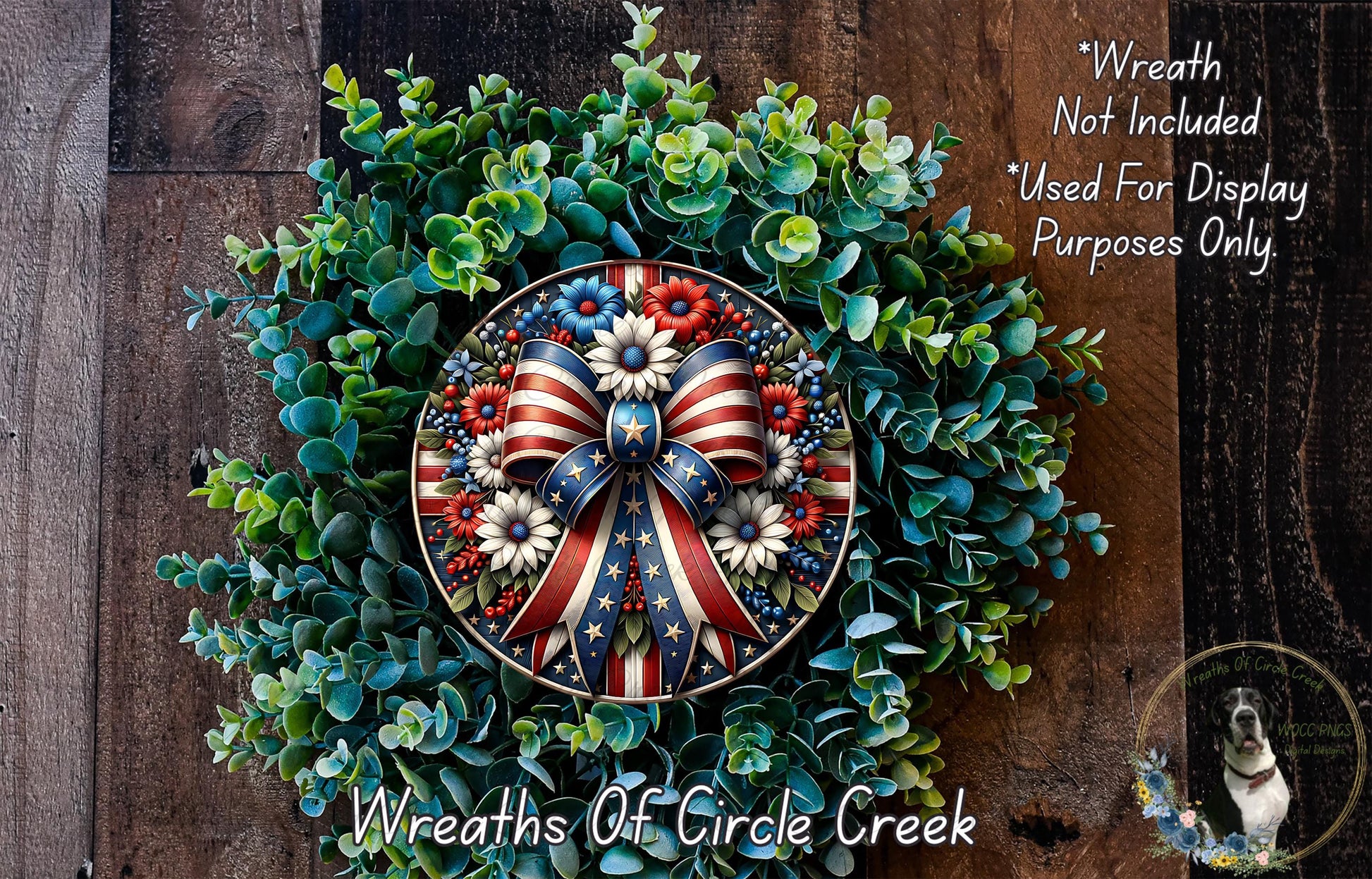 a wreath with a patriotic design, including a large American flag-themed bow and flowers. The wreath is displayed on a wooden surface, and there is a small dog in the bottom right corner of the image.