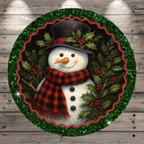 A snowman wearing a black top hat and a red and black plaid scarf, surrounded by holly leaves and berries, is depicted in a festive holiday scene.