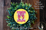 A wreath made of green leaves and a yellow and white chevron pattern, with a circular sign in the center that says "Crawfish Season".