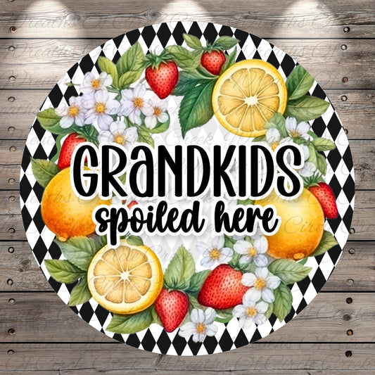 A decorative sign with a black and white checkered pattern, surrounded by various fruits such as strawberries, oranges, and lemons. The sign also features the text "GRANDKIDS spoiled here".
