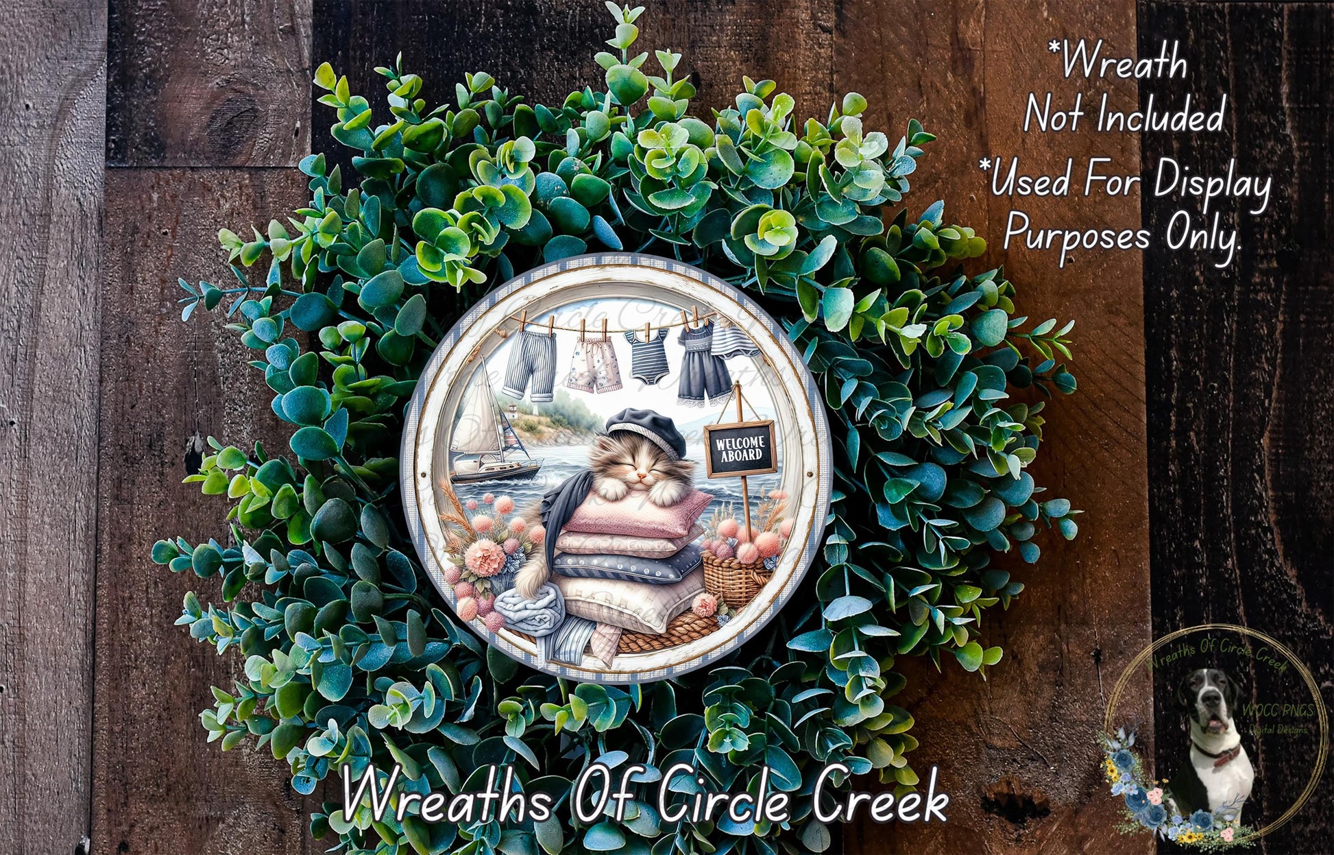A wreath made of green leaves and flowers, with a decorative plate featuring a cat and a sailboat in the center.