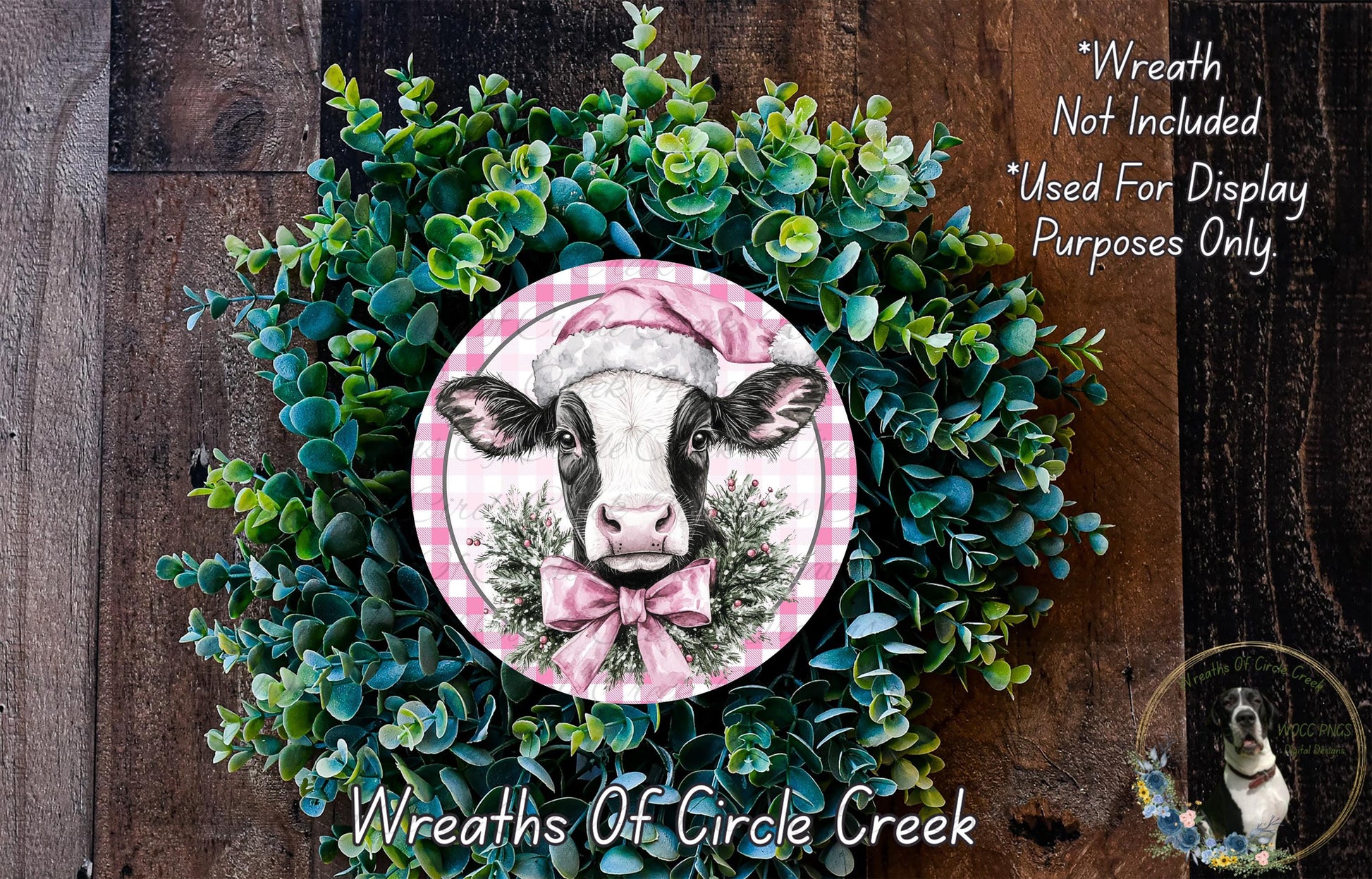 a wreath with a cow wearing a pink hat, surrounded by green foliage. The wreath is displayed on a wooden surface, and there is a text overlay that reads "Wreath Not Included * Used For Display Purposes Only" and "Wreaths of Circle Creek".