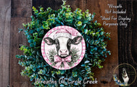 a wreath with a cow wearing a pink hat, surrounded by green foliage. The wreath is displayed on a wooden surface, and there is a text overlay that reads "Wreath Not Included * Used For Display Purposes Only" and "Wreaths of Circle Creek".