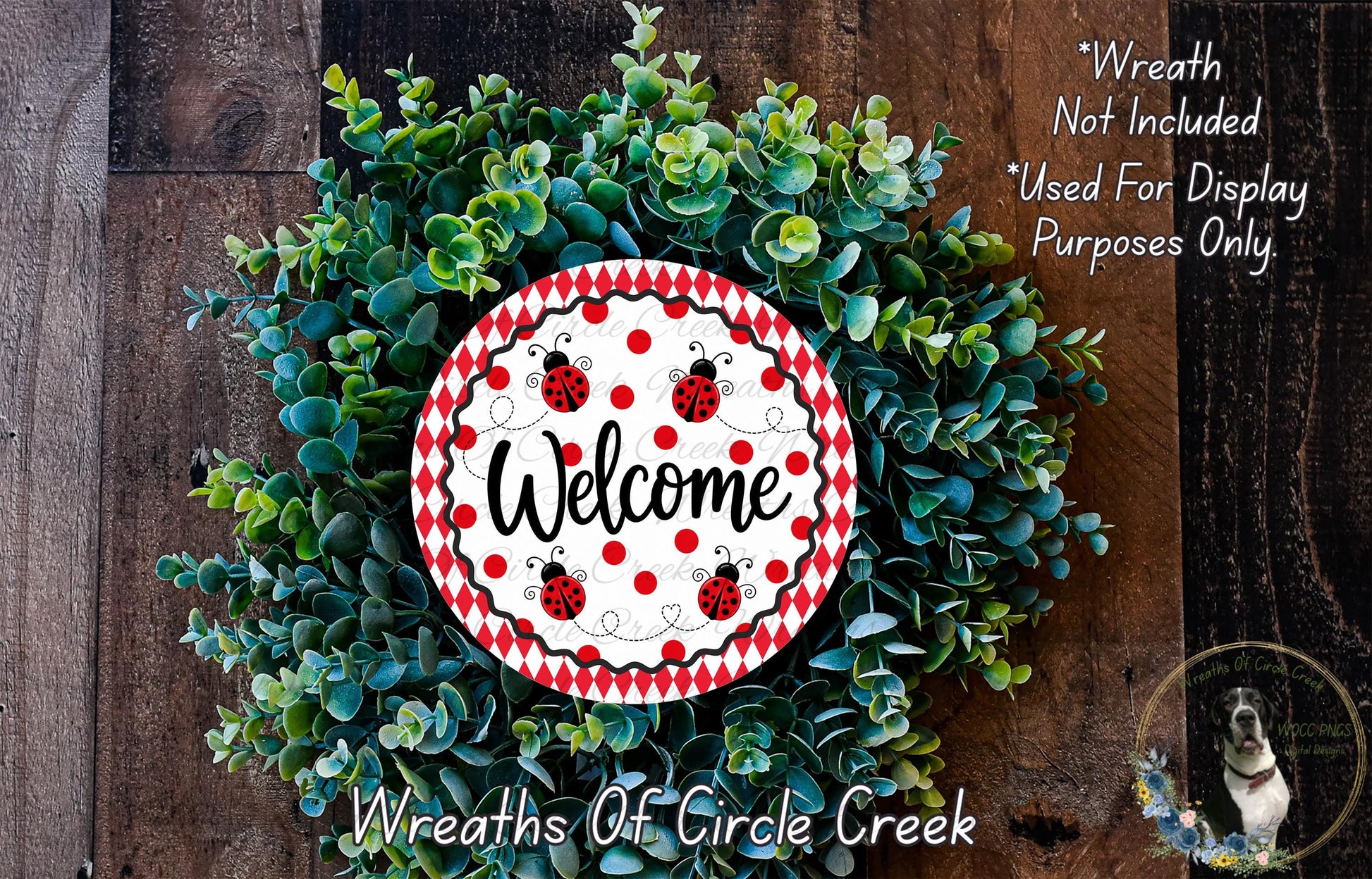 a wreath made of green leaves and a red and white welcome sign with ladybugs, placed on a wooden surface.