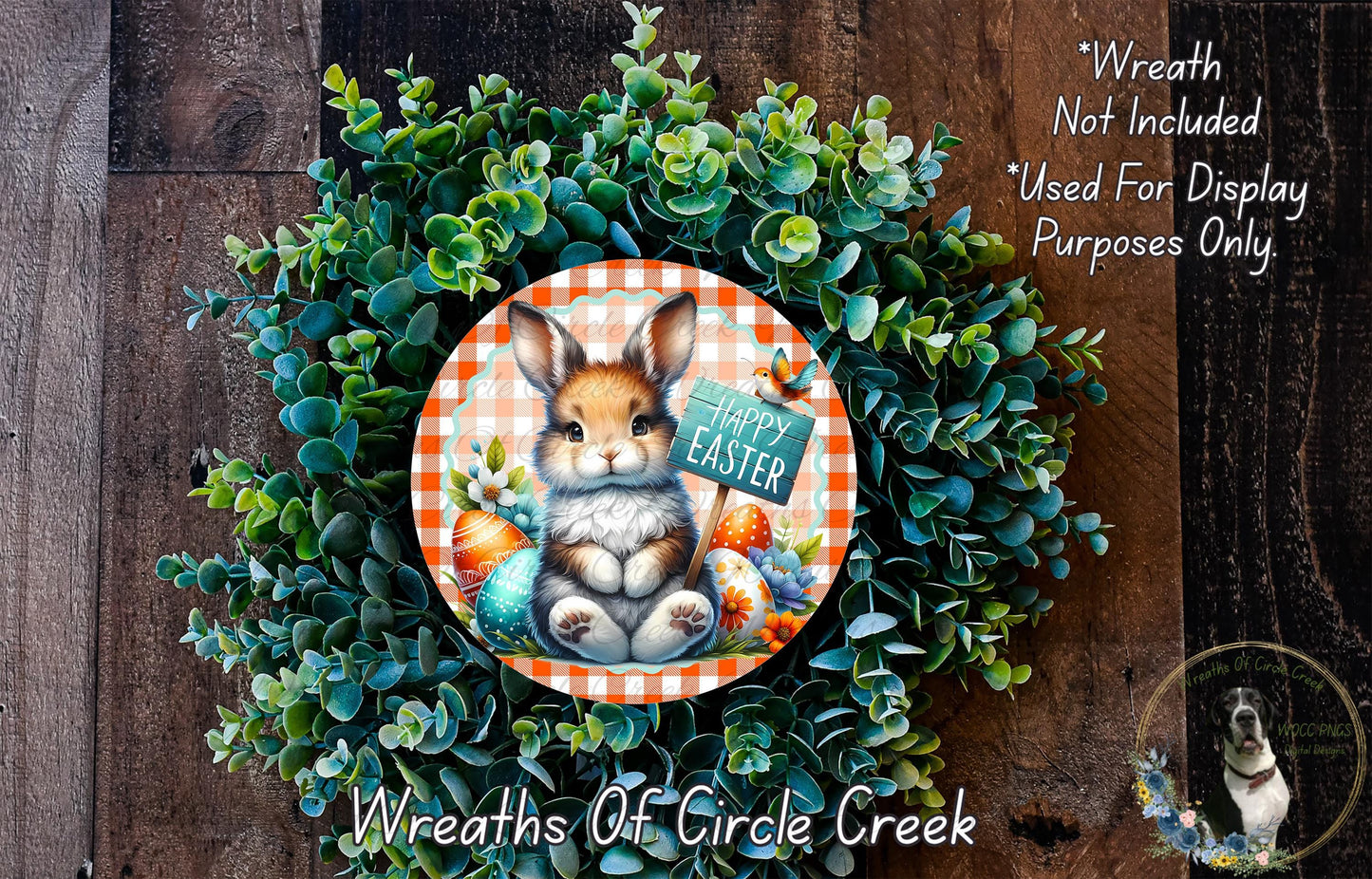 A wreath made of green foliage and featuring a brown rabbit sitting in the center, surrounded by Easter eggs and flowers. The wreath has a sign that says "Happy Easter".