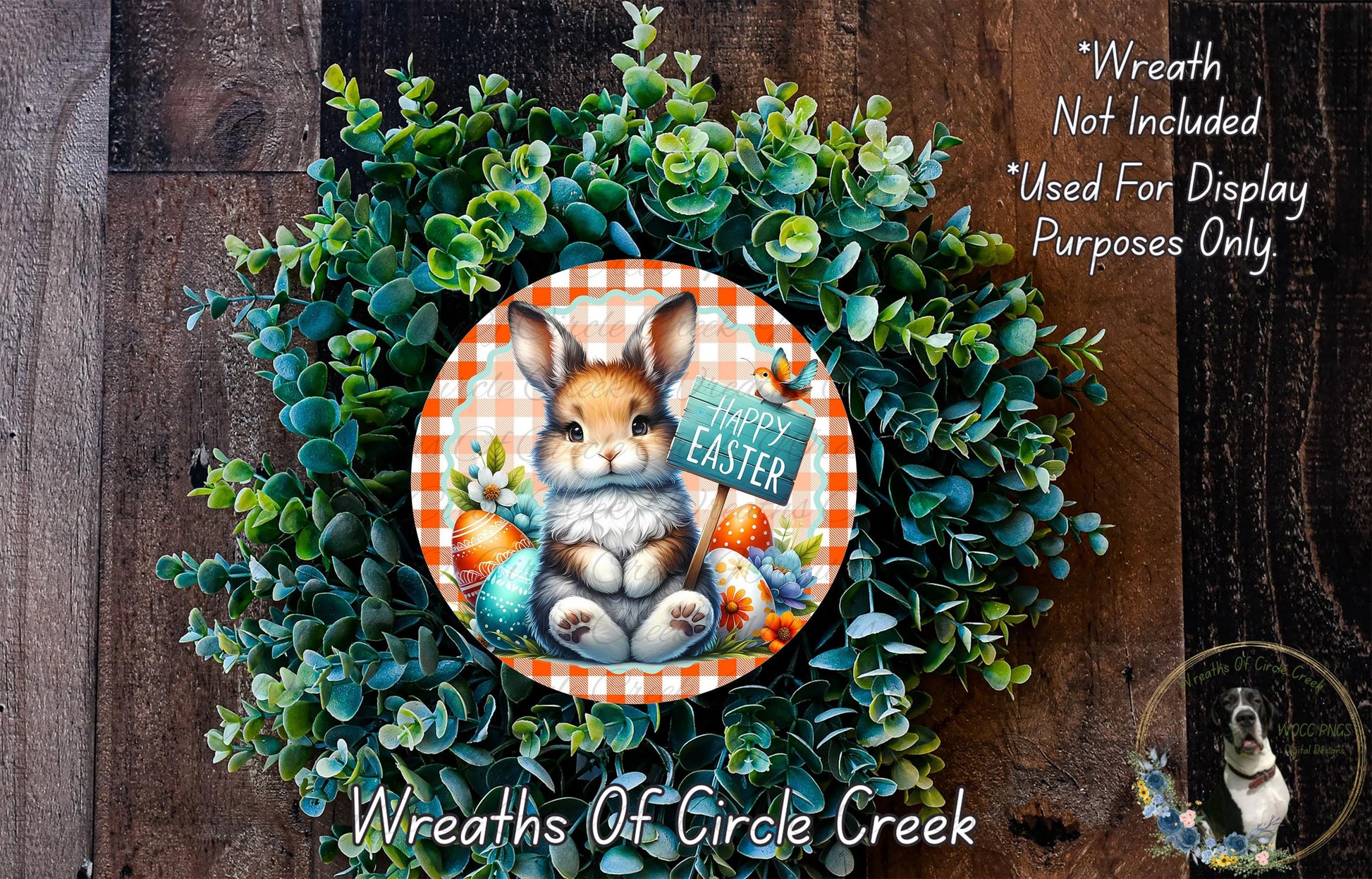 A wreath made of green foliage and featuring a brown rabbit sitting in the center, surrounded by Easter eggs and flowers. The wreath has a sign that says "Happy Easter".