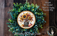 A wreath made of various green plants and flowers, with a decorative plate featuring a floral design and the text "Happy Thanksgiving".
