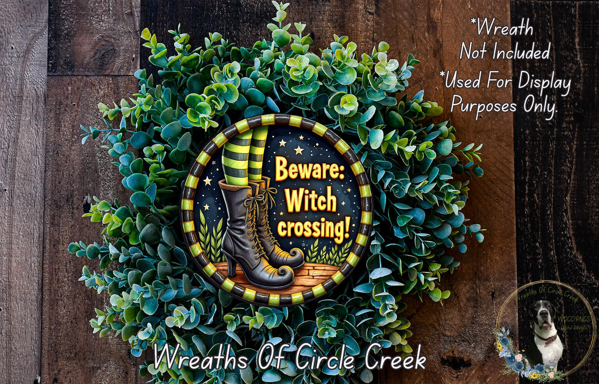 A wreath made of green leaves and a pair of black and yellow striped boots, with the text "Beware: Witch crossing!" displayed on it.