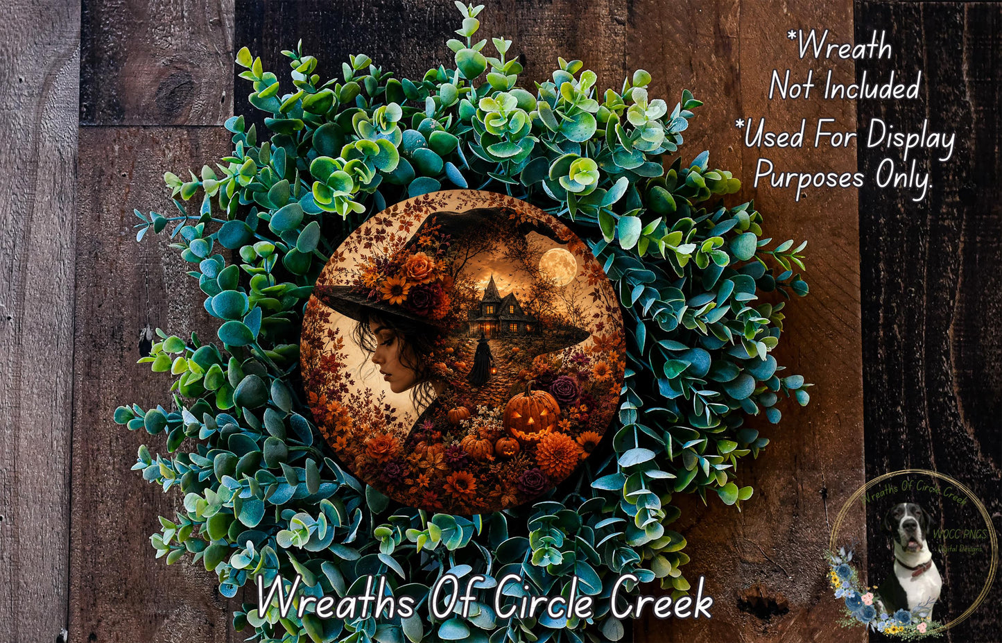 a wreath with a woman's profile in the center, surrounded by various autumn-themed elements such as pumpkins, leaves, and flowers. The wreath is displayed on a wooden surface, and there is a small dog in the bottom right corner of the image.