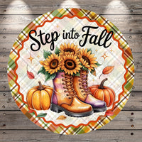 A round decorative plate with a plaid border, featuring a pair of boots, sunflowers, pumpkins, and leaves, along with the text "Step into Fall".