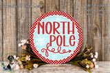 a festive wreath with the text "NORTH P Pole" written on it, surrounded by a floral arrangement and a wooden background.