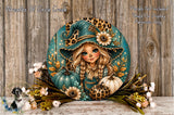 A round, decorative wreath featuring a cartoon girl with a pointed hat and floral elements, including pumpkins and flowers, set against a wooden background.