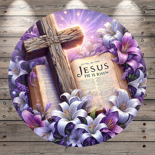 a cross surrounded by purple lilies and an open book with the text "JESUS HE IS RISEN" on it.