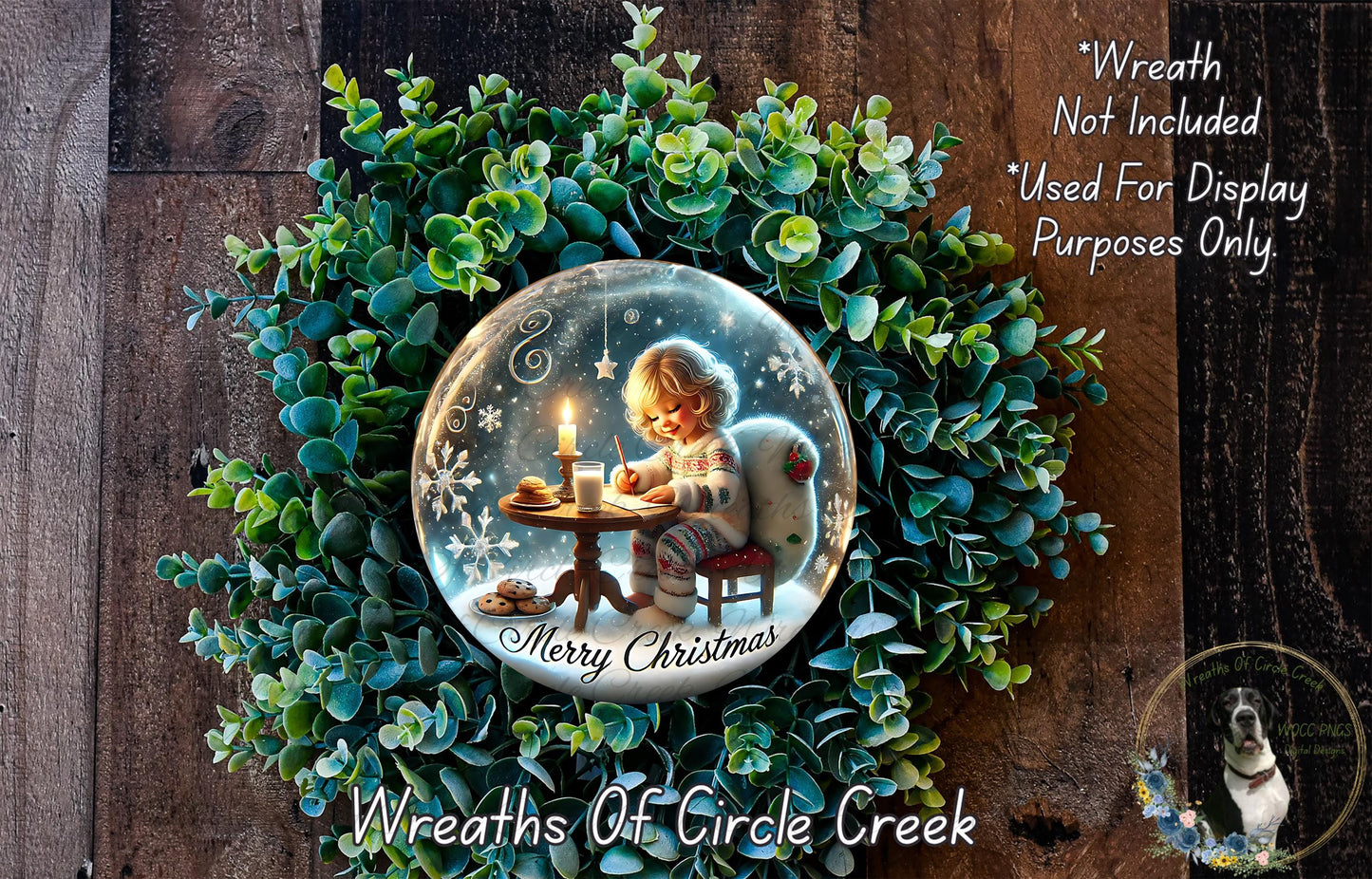 A wreath made of green leaves and a glass globe containing a child sitting at a table with a candle, surrounded by snowflakes, is displayed on a wooden surface.
