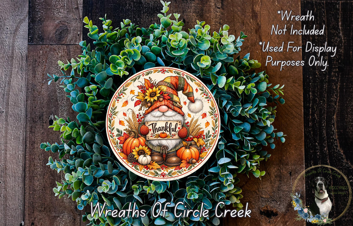 A wreath made of green leaves and autumn-themed decorations, including a gnome wearing a hat and holding a "Thankful" sign.